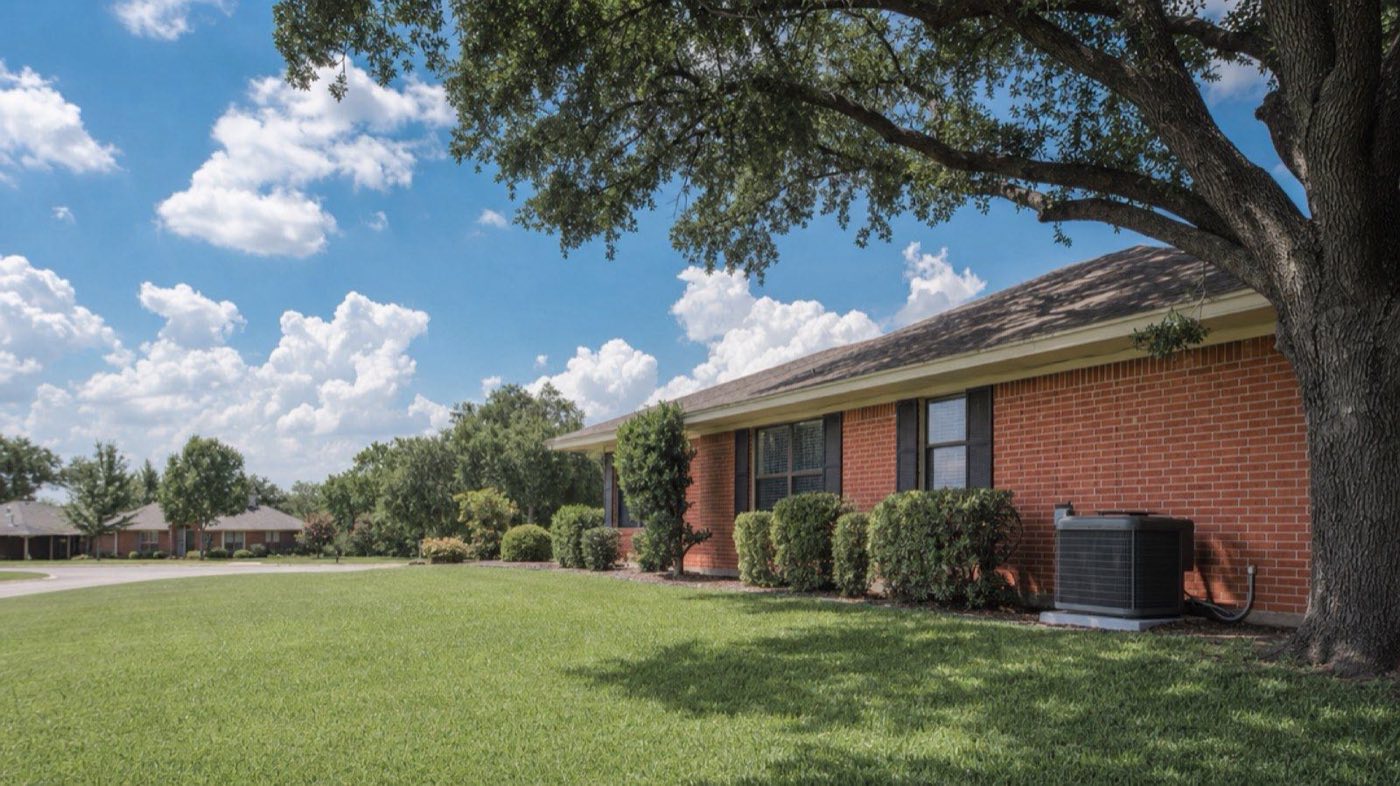 Central AC condenser beside a brick ranch home in Fort Worth under a summer sky